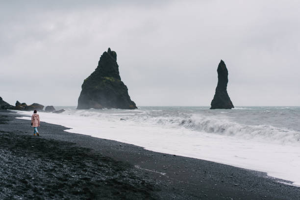 istock Woman walking on the black sand beach in Vik, Iceland 855782662