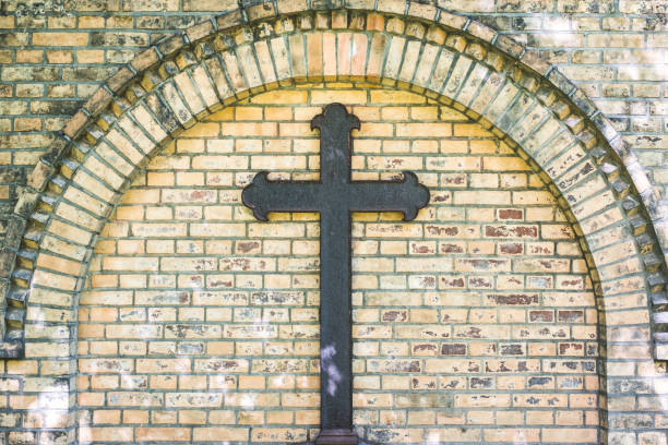 old metal cross on brick wall background , rusty cross on grave - cemetery tombstone grave old imagens e fotografias de stock
