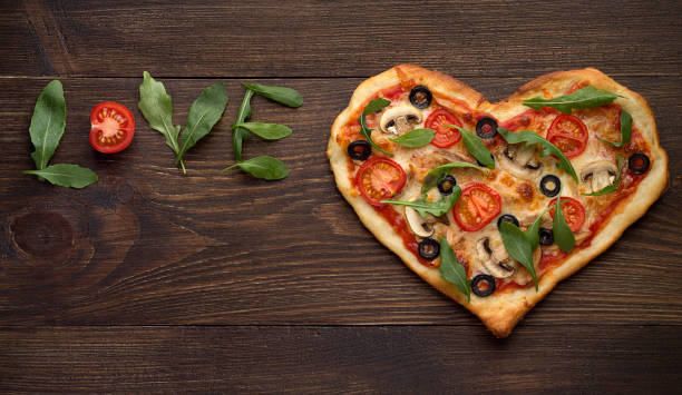 Valentines day pizza in heart shape with inscription love on dark rustic wooden background. stock photo