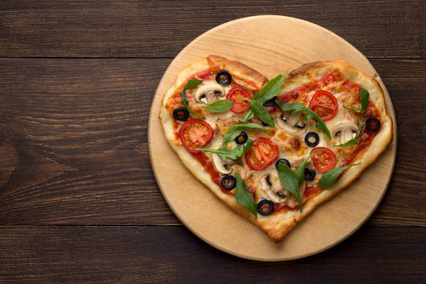 istock Heart shaped pizza on cutting board on wooden table. 855792340