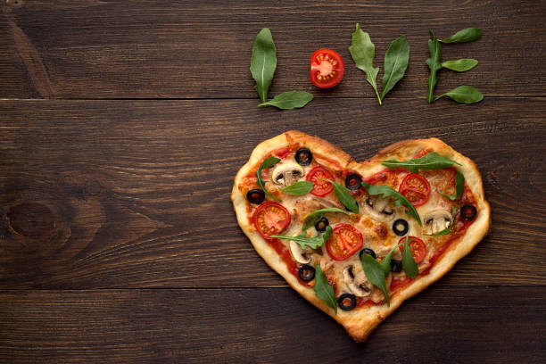 istock Heart shaped pizza for Valentines day on dark rustic wooden background with text love. 855792360