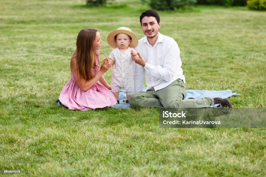 Happiness and harmony family life concept. Young mother and father with baby son in the park. Happy family resting together on the green grass Happiness and harmony family life concept. Young mother and father with baby son in the park. Happy family resting together on the green grass at summer Adult Stock Photo
