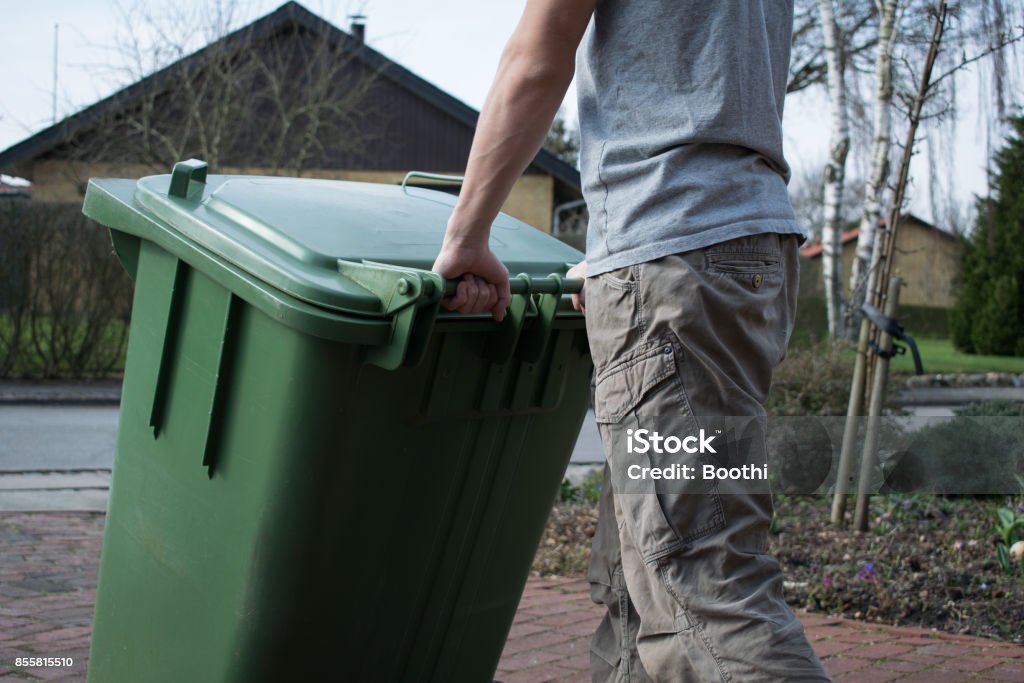 Pushing Garbage Bin Man pushing a green garbage bin Garbage Bin Stock Photo