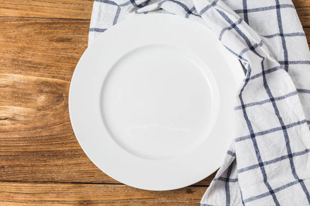istock Top view of clean empty plate on wooden tabletop with napkin 855823324