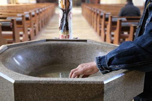 Devout Christian (roman catholic) dipping his fingers in holy water