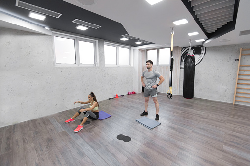 Woman having a fitness practice in the gym with her fitness instructor
