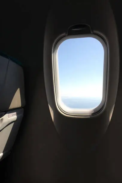 Looking out the airplane window seat into the  blue sky while flying in the air at daytime.