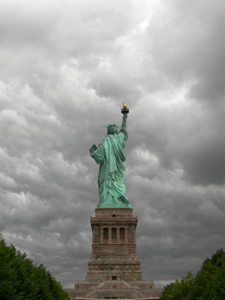 istock Statue of liberty from the back with grey and cloudy sky. 855845024