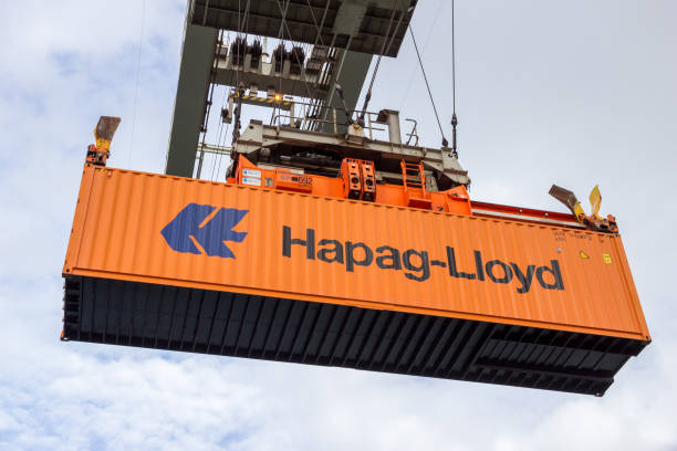 Container shipping crane ROTTERDAM - SEP 6, 2015: Crane operator picking up a Hapag-Lloyd sea container in the Port of Rotterdam. stacker stock pictures, royalty-free photos & images