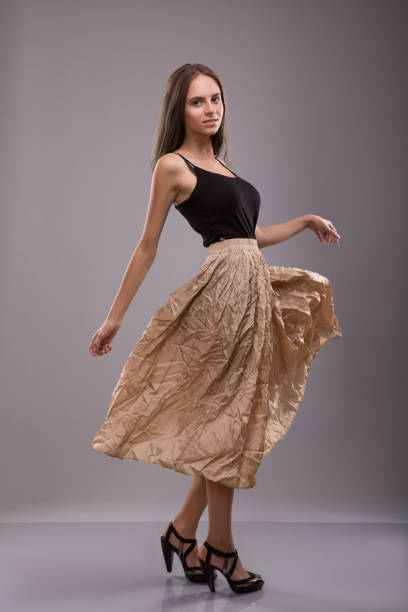 Woman dressing in Spreading skirt staying over gray background. Studio shoot