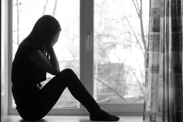 istock Woman sitting on windowsill, crying 855848744