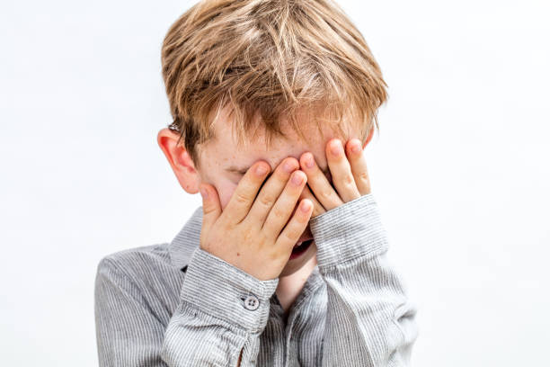 istock little boy covering his face for playing peekaboo or disappearing 855848836
