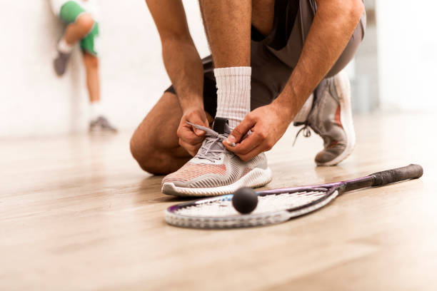 squash player tying shoelaces - racket ball indoors competition imagens e fotografias de stock
