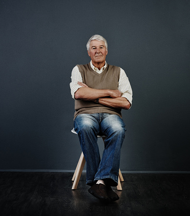 Studio portrait of a handsome mature man posing with his arms crossed against a dark background