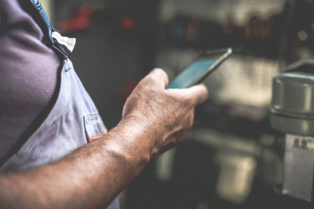 istock Senior man in workshop. Man holding mobile and reading text. Close up. 855860334