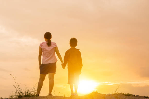 istock Mother and their son standing holding hands and watching sunset 855861002