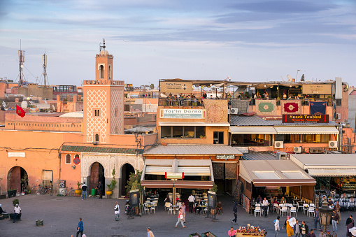 MARRAKECH, MOROCCO - APR 29, 2016: Mosque and restaurants with tourists on the Djemaa-el-Fna square in Marrakech.