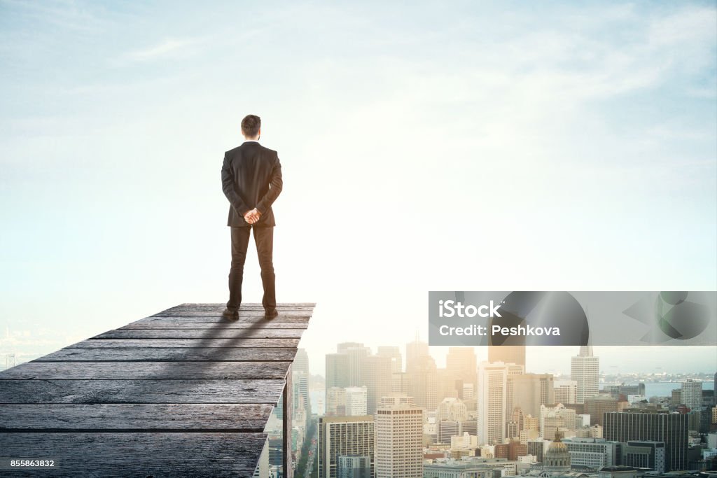 Research concept Back view of young businessman on wooden pier looking at city with copy space. Research concept Horizon Stock Photo