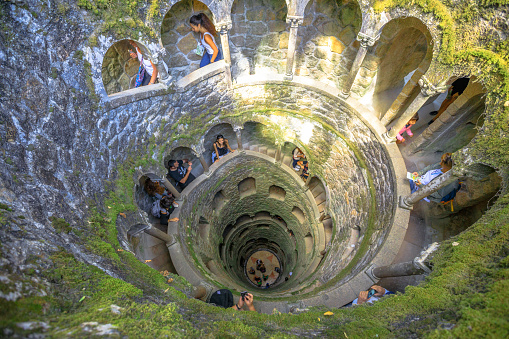 Sintra, Portugal - August 9, 2017: tourists inside the iconic Initiation well a masonic underground passage in Quinta da Regaleira.World Heritage Site by Unesco within the Cultural Landscape of Sintra