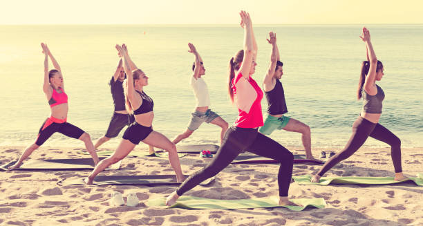 istock People exercising yoga poses on beach 855867284