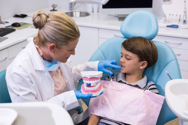 istock High angle view of dentist holding dental mold while examining boy 855870374