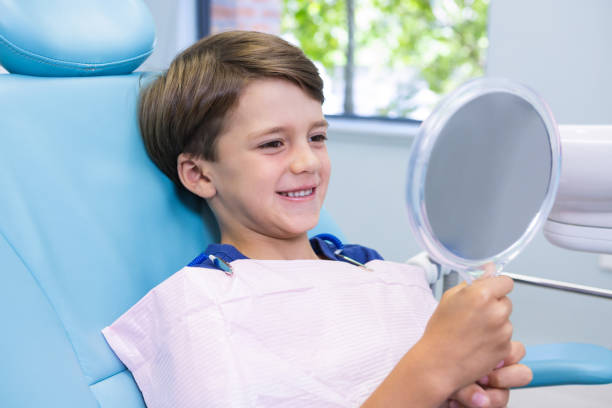 istock Cute boy looking at mirror while sitting on chair 855871666