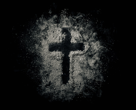 A cross drawn out in a pile of ashes