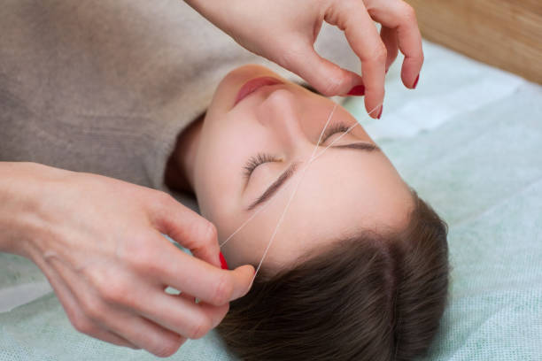 istock make-up artist corrects makeup, gives shape and thread plucks eyebrows in a beauty salon 855880274