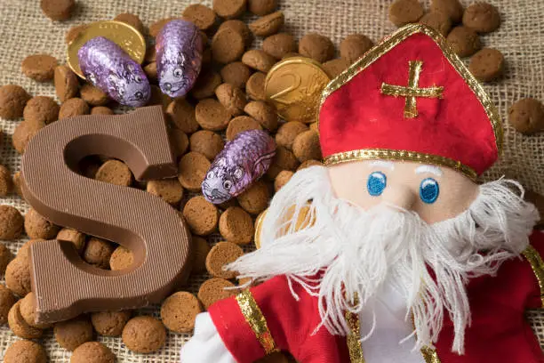 Photo of flat lay, candy, present, fake coins, ginger nuts with chocolate letter, against white background, for the fifth of December, event