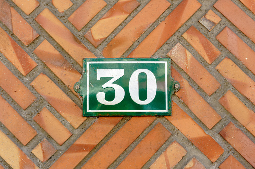 Old vintage house address blue metal number 99 ninety nine on the brick facade of residential building exterior wall on the street side