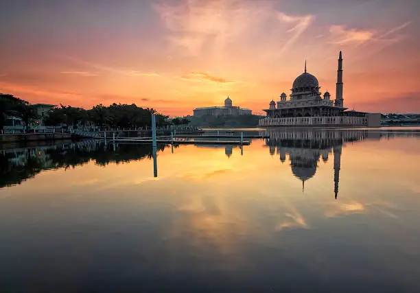 Photo of Beautiful sunrise view over Putrajaya with Putra Mosque and Putra Perdana Building as background with soft focus reflection effect