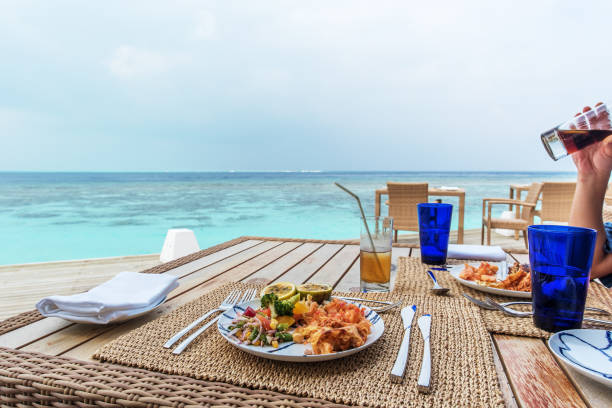 Wooden furniture perched on grassy cliff edge, offering panoramic view of turquoise Mtende Beach waters in Zanzibar, presenting peaceful coastal relaxation scene