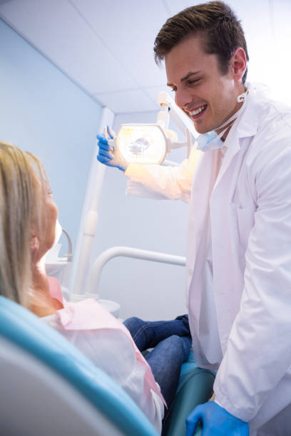 istock Dentist adjusting lamp while looking at patient in clinic 855898436