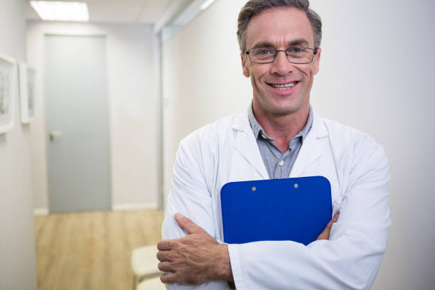 istock Dentist holding file while standing at lobby in dental clinic 855902480