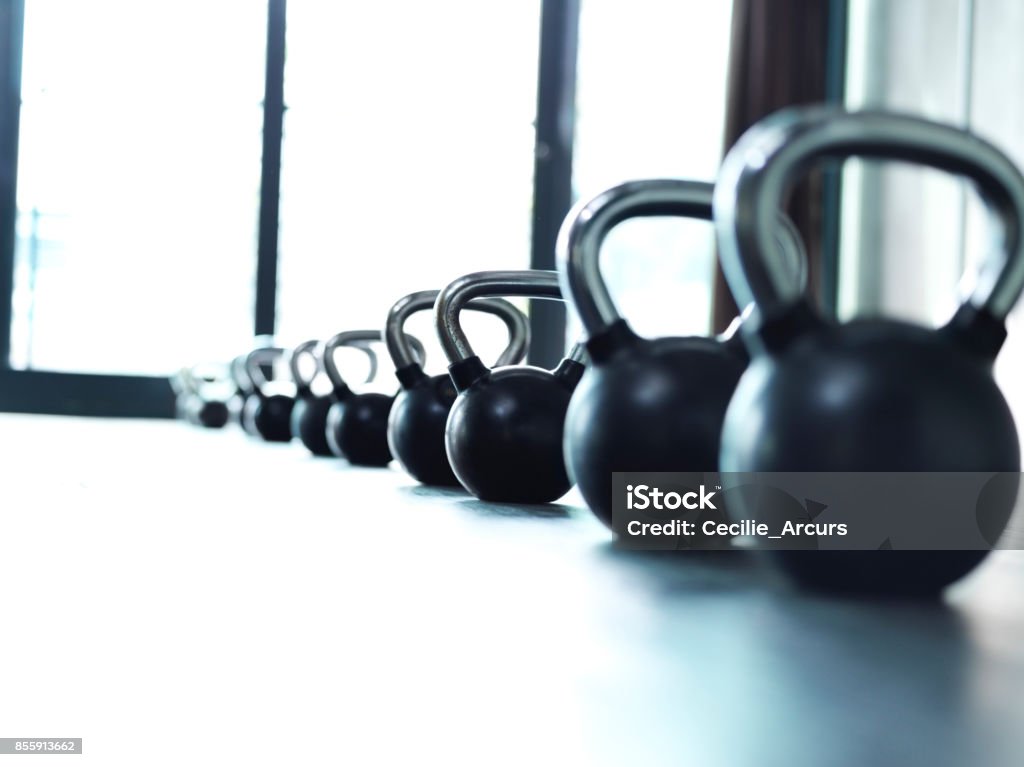 Weights, they do a body good Shot of a bunch of kettle bells lined up in a row on the floor of a gym Exercise Equipment Stock Photo