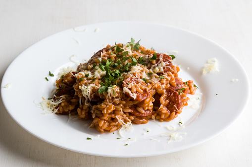 Chorizo risotto with tomato and red wine on white plate