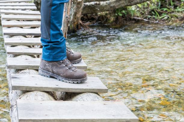 istock Hiking boots on tree trunk bridge over a creek 855932128
