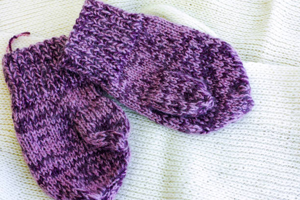 istock Two purple knitted mittens on white scarf. 855940094