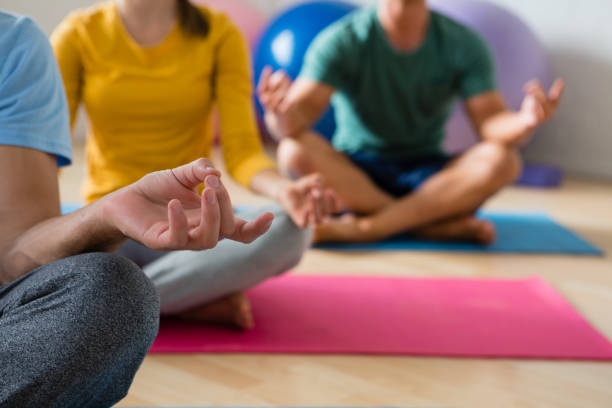 istock Midsection of yoga instructor with students meditating in lotus position 855959294