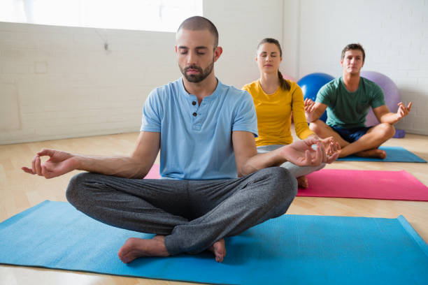 istock Yoga instructor with students meditating at club 855959370
