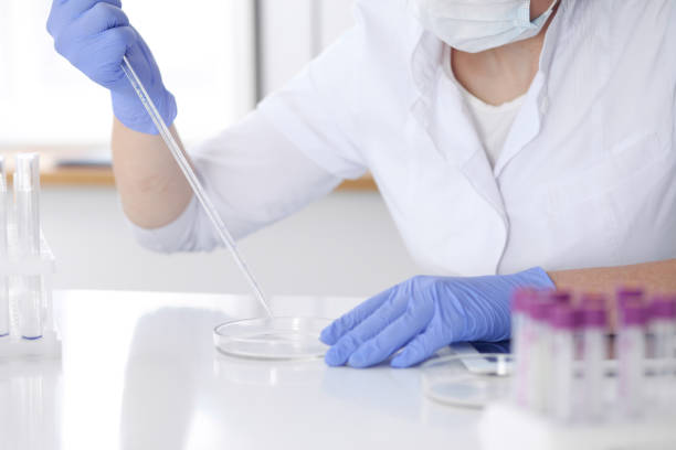 istock Close-up of professional female scientist in protective eyeglasses making experiment with reagents in laboratory. Medicine and research concept 855983464