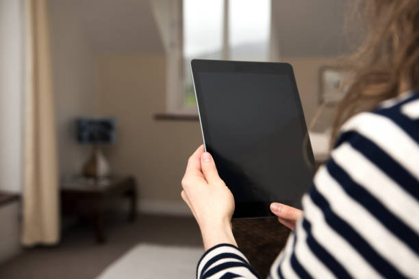 istock Young blond woman is sitting at home holding a tablet computer in her hands. 855984952
