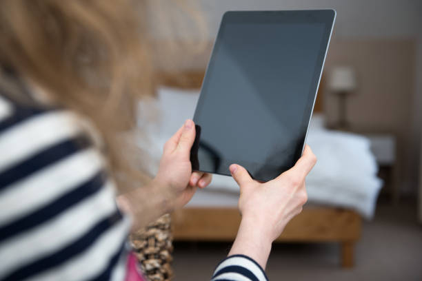 istock Young blond woman is sitting at home holding a tablet computer in her hands. 855984958