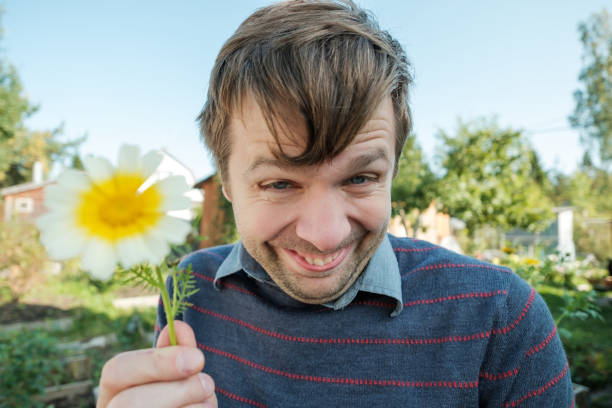 istock Funny young man smiles silly and gives a daisy. 855985124