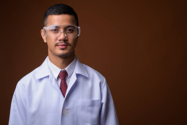 istock Studio shot of young multi-ethnic Asian man doctor wearing protective eyeglasses against colored background 856001472