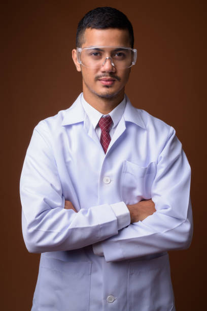 istock Studio shot of young multi-ethnic Asian man doctor wearing protective eyeglasses against colored background 856001482