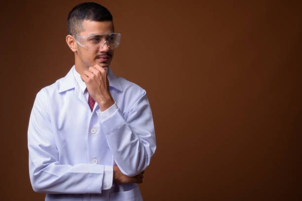 istock Studio shot of young multi-ethnic Asian man doctor wearing protective eyeglasses against colored background 856002510