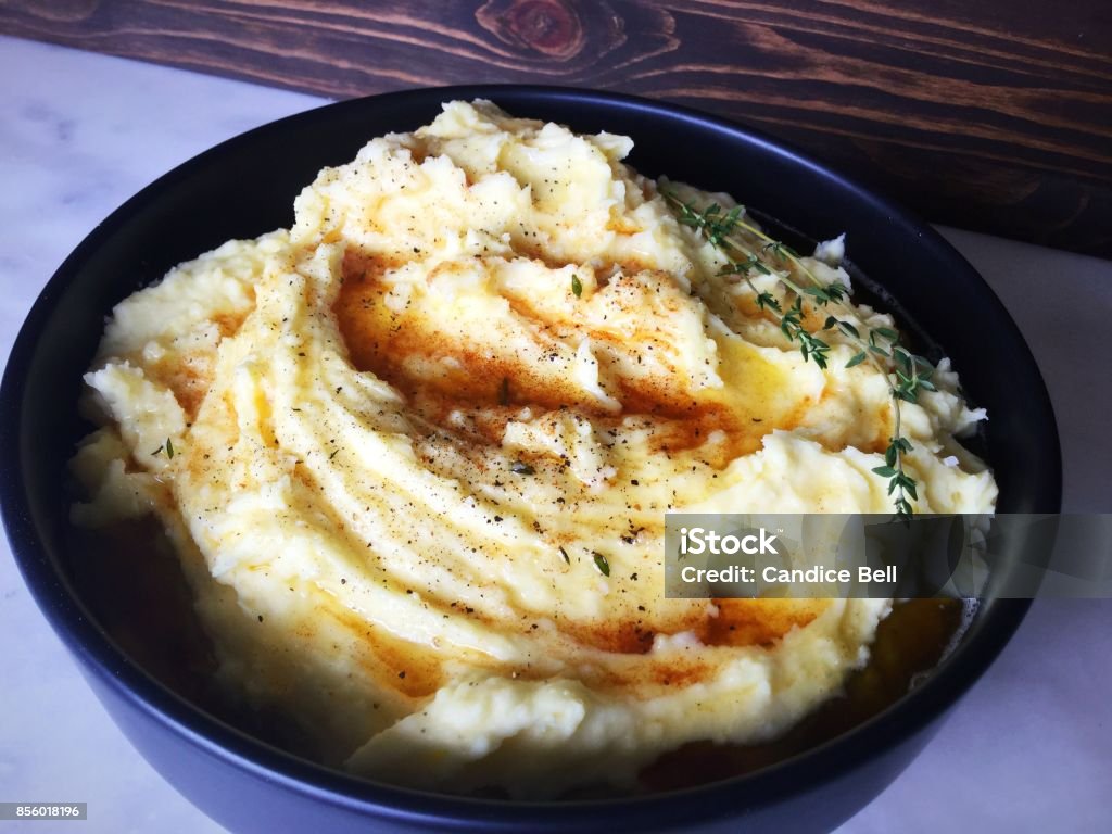 Mashed Potatoes with Thyme Infused Brown Butter A large bowl of mashed potatoes topped with brown butter and garnished with a sprig of thyme. Mashed Potatoes Stock Photo