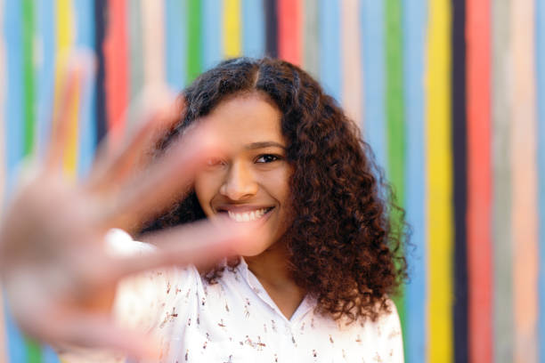 istock Smiling woman hiding her face with palm, looking at camera 856018276
