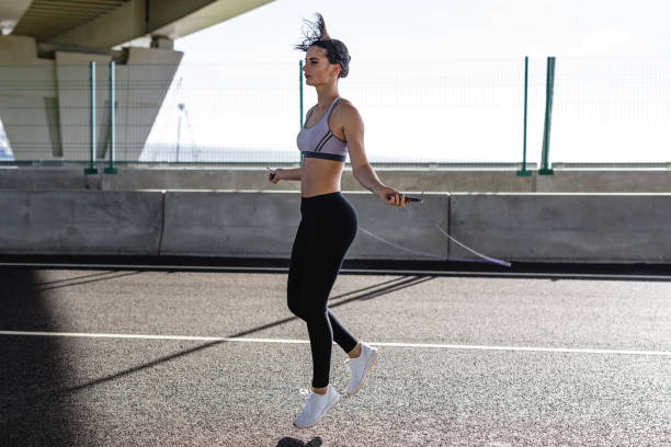istock Young woman jumping with skipping rope, doing exercises outdoors 856018314